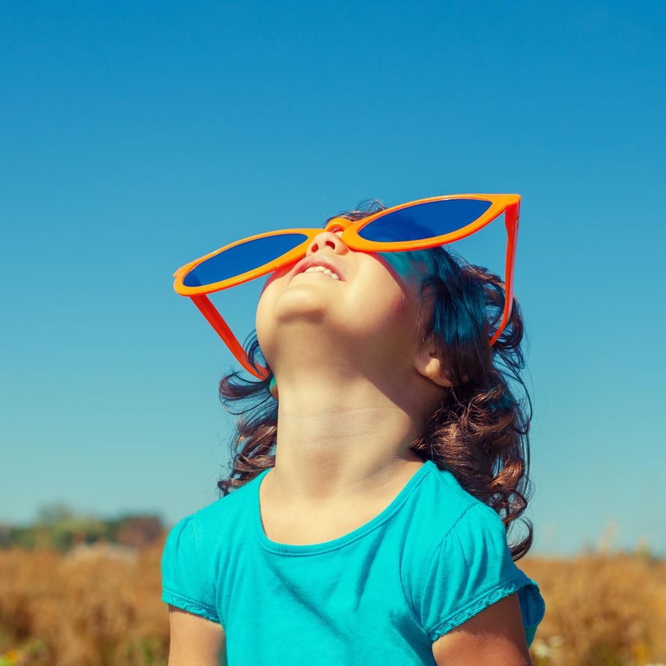Sinn des Lebens: Ein Kind schaut mit riesiger Sonnenbrille auf der Nase in den Himmel