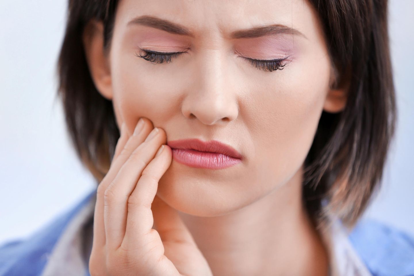 Zahnschmerzen Hausmittel: Frau hält sich die Wange