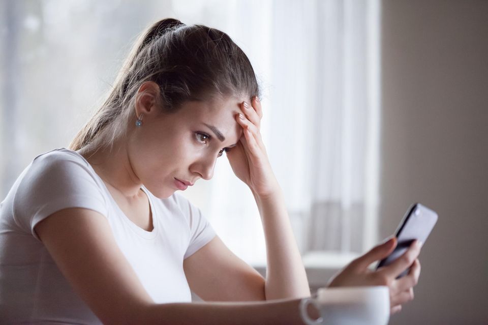 Ist Neid ein Kompliment? Eine junge Frau guckt neidisch auf ihr Handy