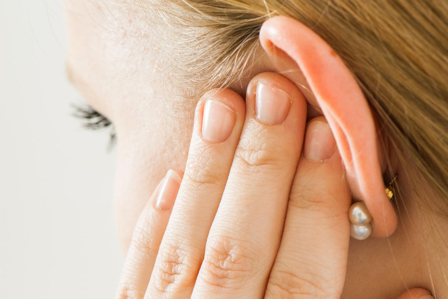 Ohrenschmerzen: Frau fasst sich ans Ohr