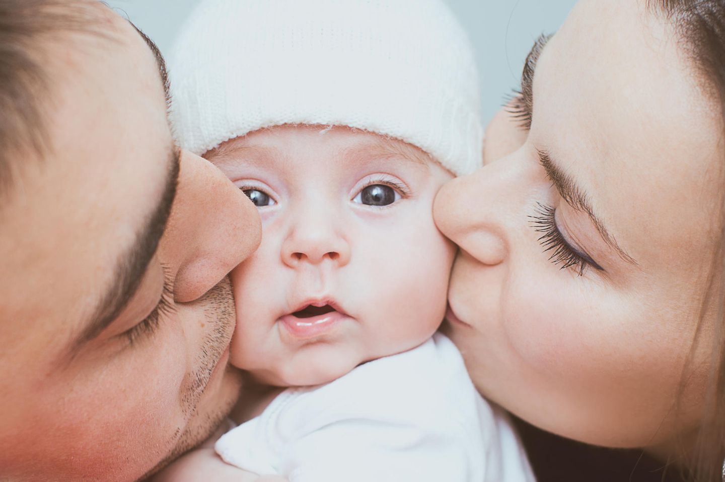 Was macht die Elternzeit mit der Beziehung: Eltern küssen Baby