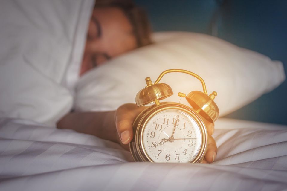 Snooze-Taste: Frau umfasst Wecker