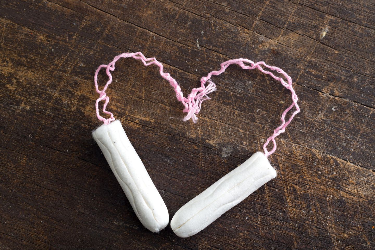 Tampon einführen: Zwei Tampons auf einem Holztisch zum Herz geformt