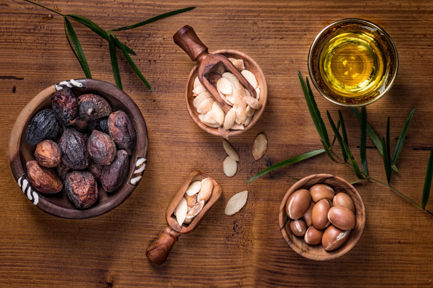 Arganöl für die Haut: Argannüsse, Argankerne und Arganöl in einer Schale stehen auf einem Holztisch