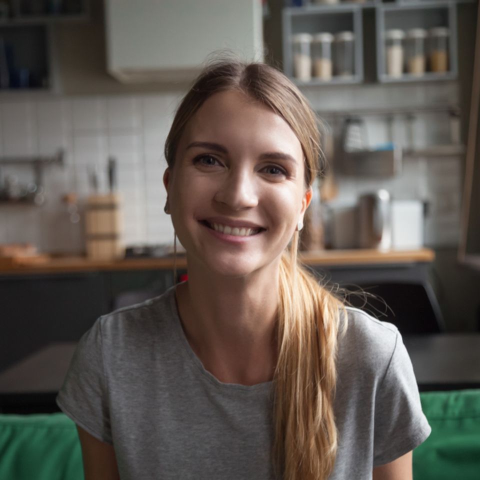 WG-Casting: Junge Frau sitzt lächelnd auf einem Sofa in der Küche