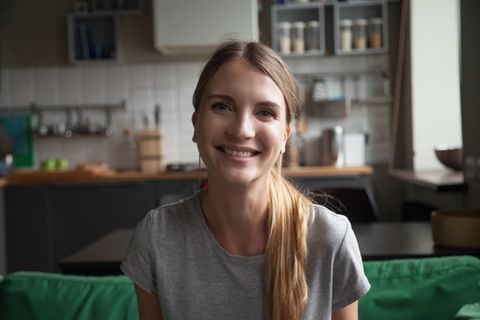 WG-Casting: Junge Frau sitzt lächelnd auf einem Sofa in der Küche