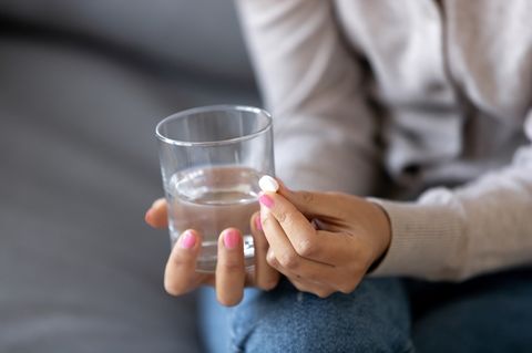 Medikamente bei Depressionen: Wann helfen sie? Frau hält Tablette und Wasserglas in der Hand