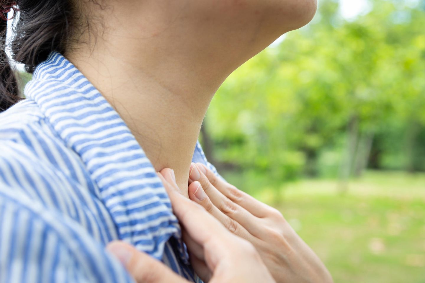 Hausmittel bei Mandelentzündung: Frau fasst sich an den Hals