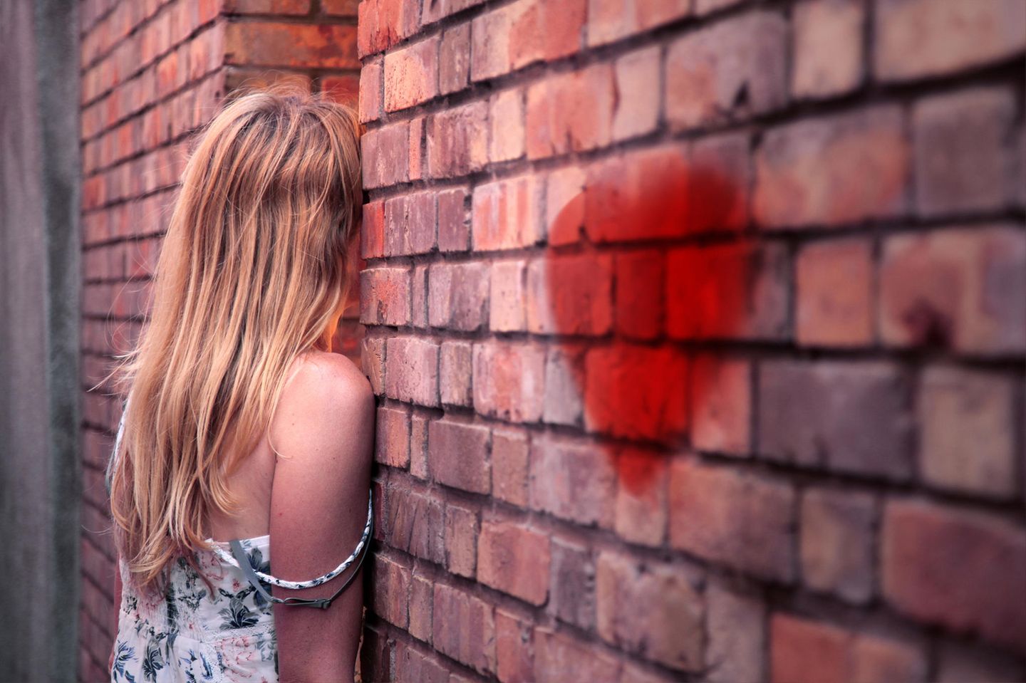 Unerwiderte Liebe: Eine junge Frau steht mit dem Gesicht zur Wand