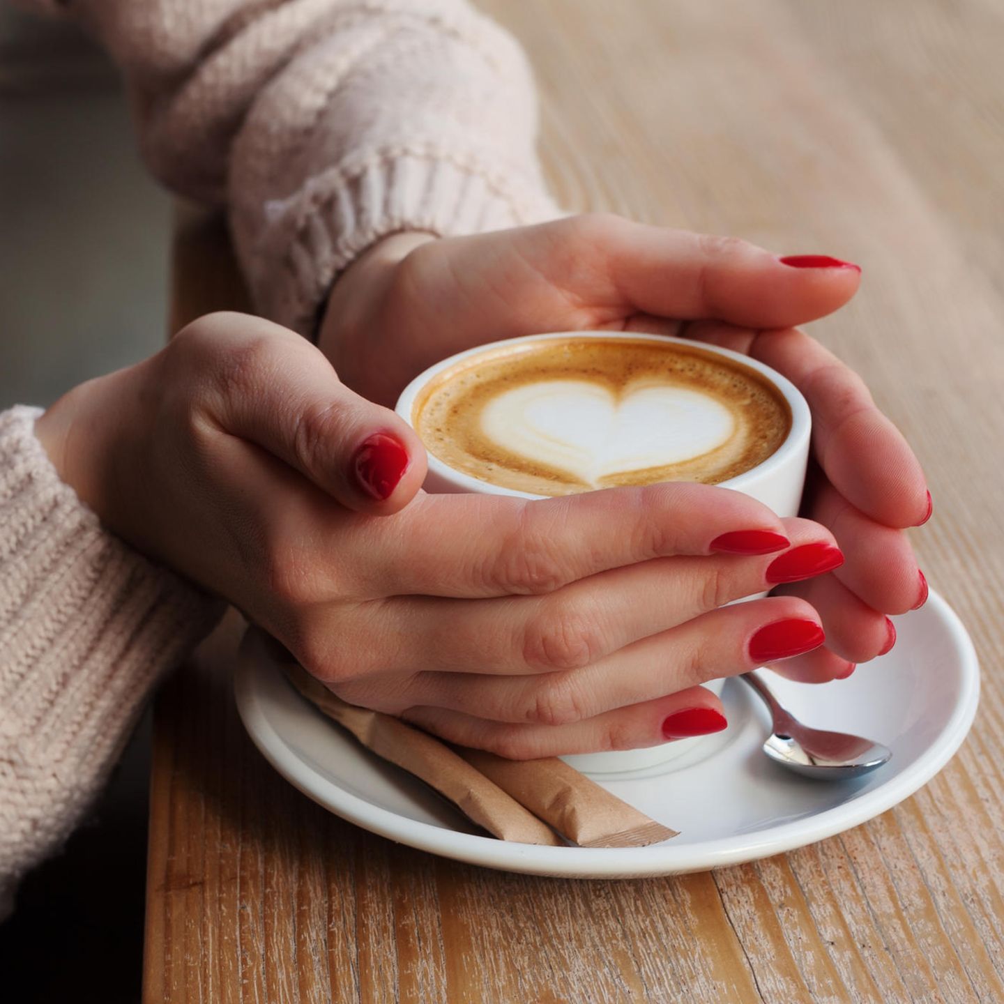 Frau hält einen Milchkaffee in den Händen