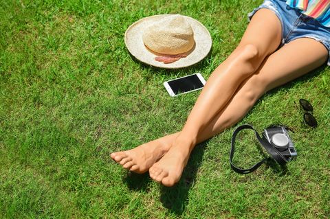 Sonnenallergie vorbeugen: Frau sonnt sich auf Wiese