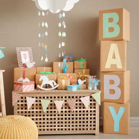 Geschenke zur Geburt - Gschenke auf einer Holzbox gestapelt, daneben große Letter und das Wort Baby