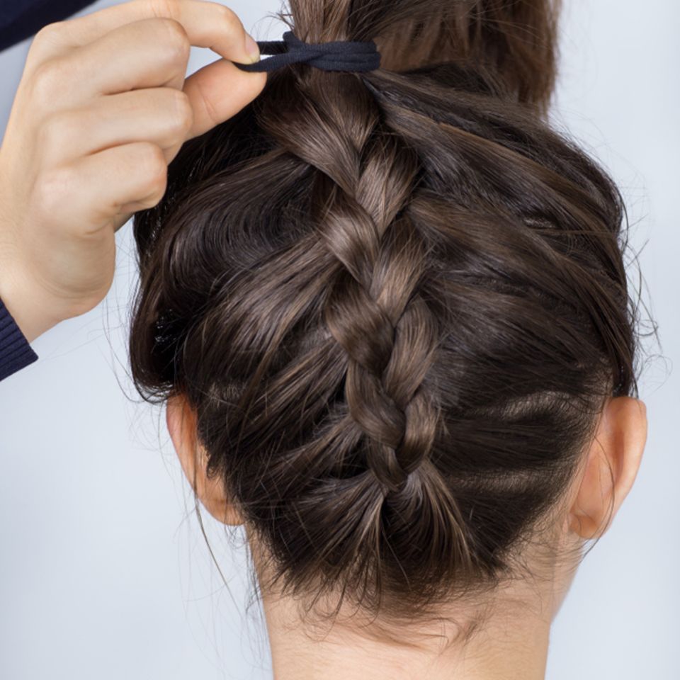 Einfache Frisuren: Geflochtener Zopf wird mit einem Haarband zusammengebunden