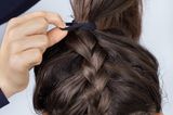 Einfache Frisuren: Geflochtener Zopf wird mit einem Haarband zusammengebunden