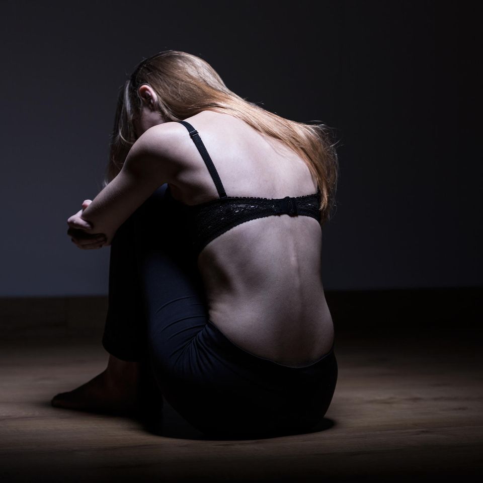 Magersucht: Sehr dünne Frau sitzt auf dem Boden