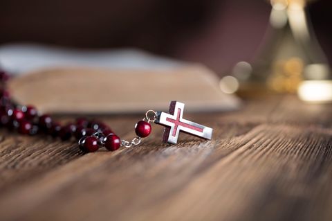 Glückwünsche zur Konfirmation: Kreuzanhänger liegt auf Tisch
