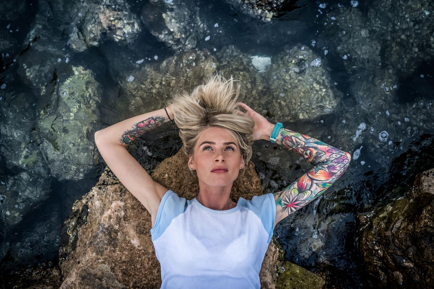 Was Tattoos über Menschen aussagen: Tätowierte Frau liegt am Wasser