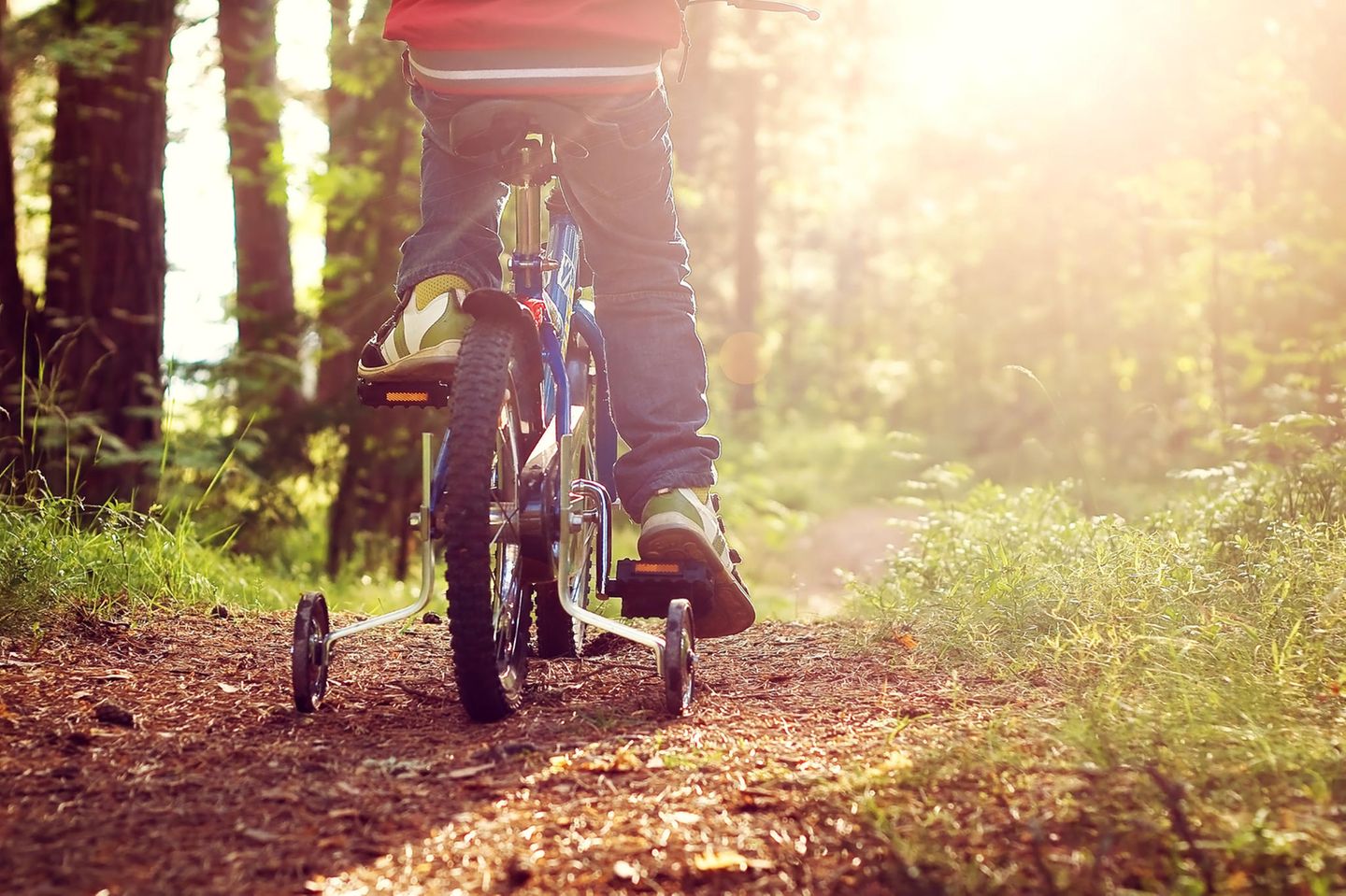 Fahrrad fahren lernen: Junge fährt mit Stützrädern