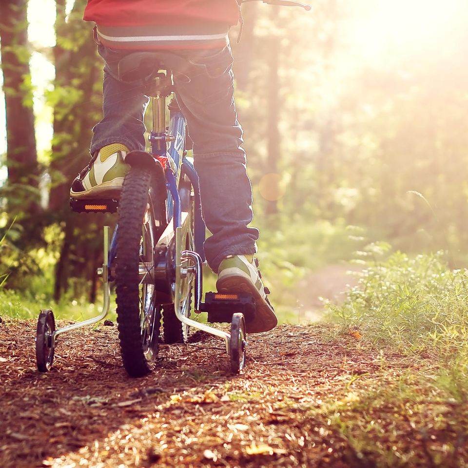 Fahrrad fahren lernen: Junge fährt mit Stützrädern