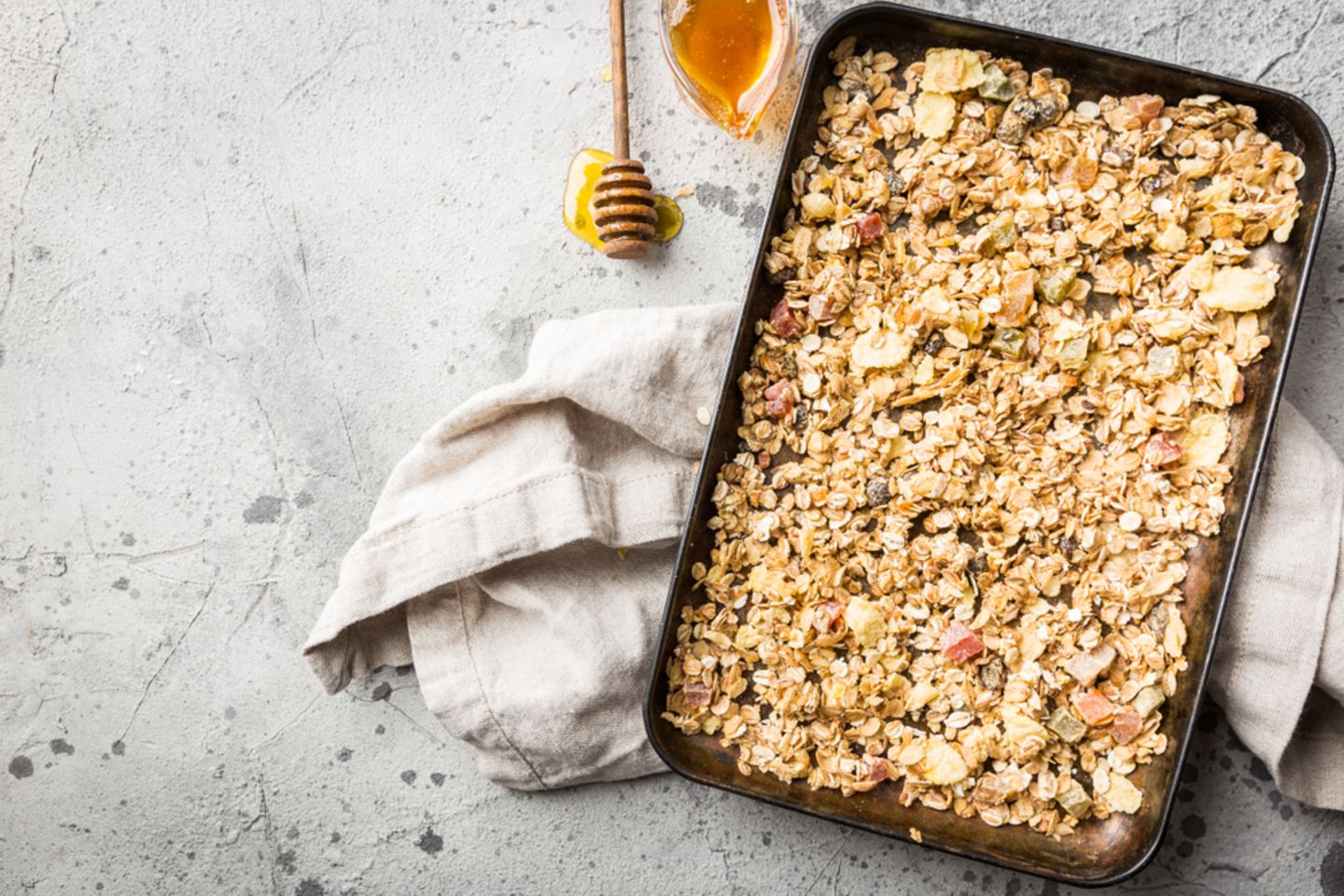 Baked Oatmeal: Auflaufform mit Haferflockenauflauf von oben, daneben ein Glas mit Honig
