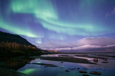 Polarlichter: See und Berge im Himmel grüne und lilafarbene Polarlichter