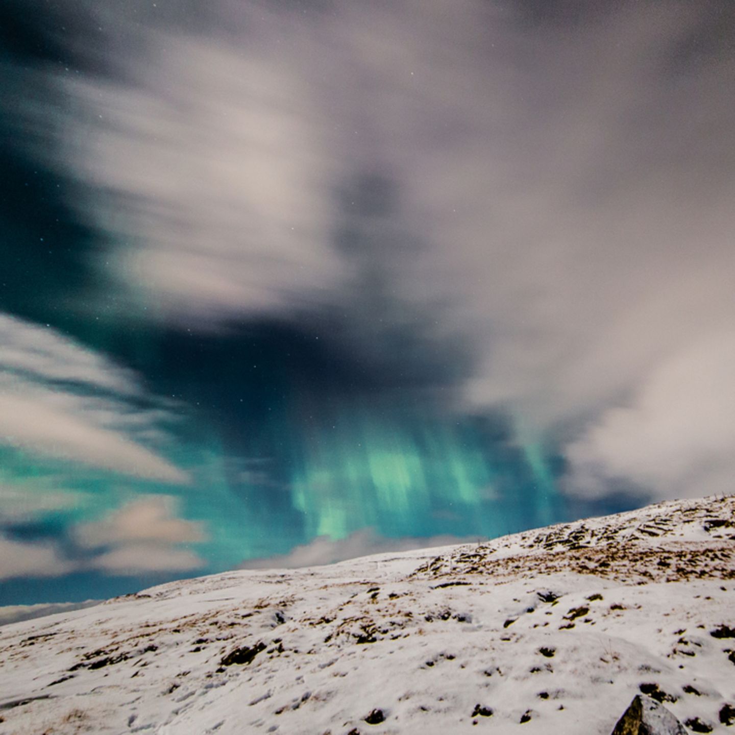 Polarlichter: Schneebedeckter Berg, im Himmel grüne Polarlichter