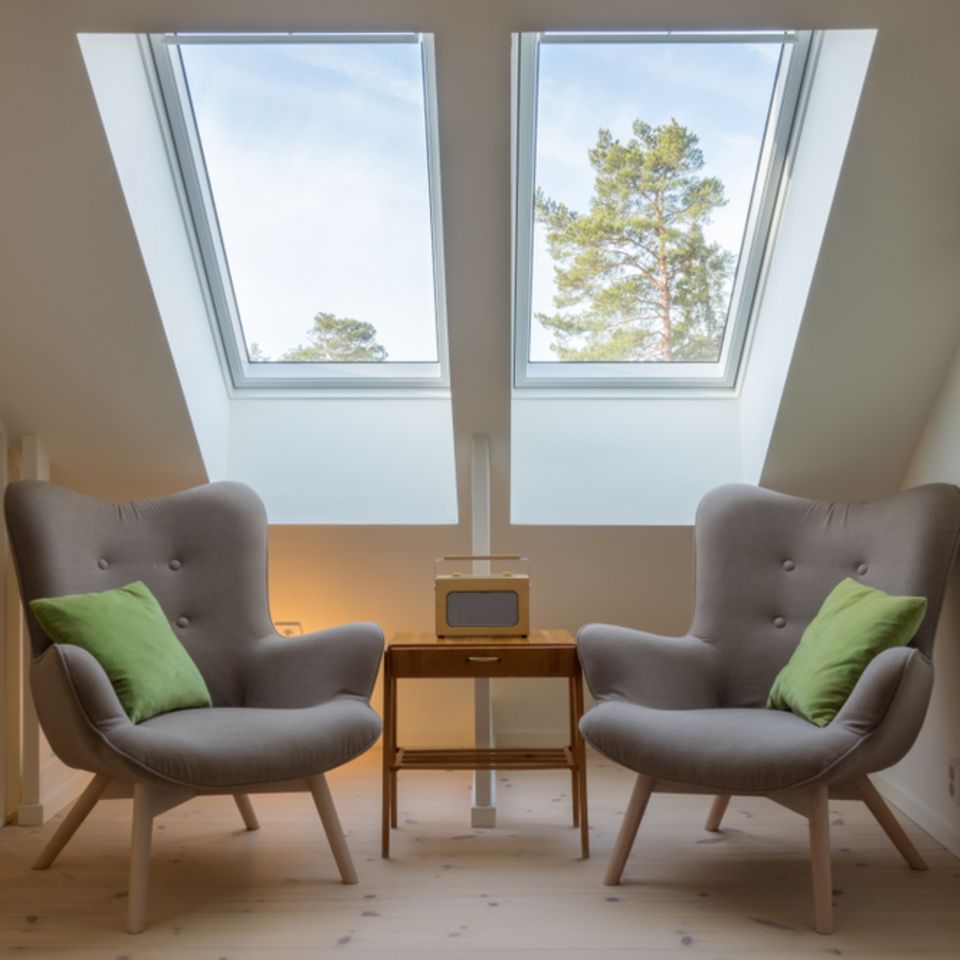 Zwei Sessel stehen unter Dachfenstern