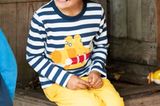 Kindermode: Junge in gelber Hose sitzt auf Kiste