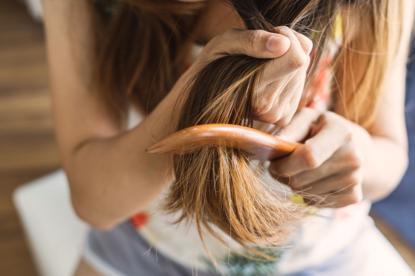 Strohige Haare pflegen: Frau kämmt ihre Haarspitzen