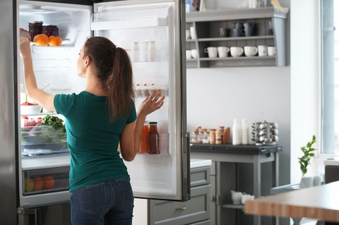 Kühlschrank richtig einräumen: Frau sortiert Kühlschrank ein