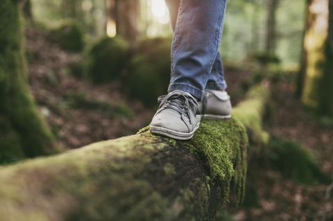 Trick gegen Burnout: Frau balanciert auf einem Baumstamm