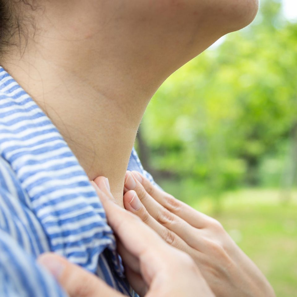 Hausmittel gegen Kehlkopfentzündung: Frau fasst sich an den Hals