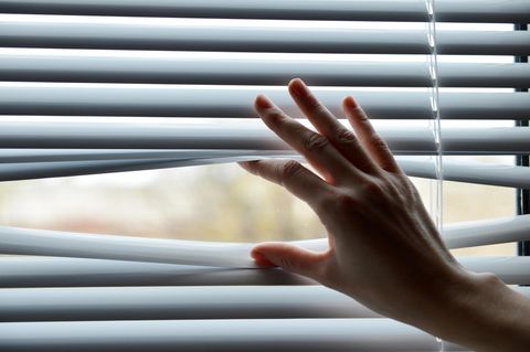 Fenster verdunkeln: Frau schiebt Jalousien nach oben
