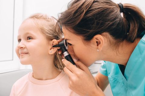 Mittelohrentzündung beim Kind: Ärztin untersucht Mädchen am Ohr