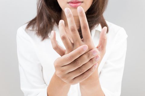 Sehnenreizung: Anzeichen, Ursachen und Behandlung: Frau hält ihre linke Hand