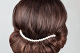 Frisuren selber machen: Frau mit eingedrehten Haaren und Perlenband