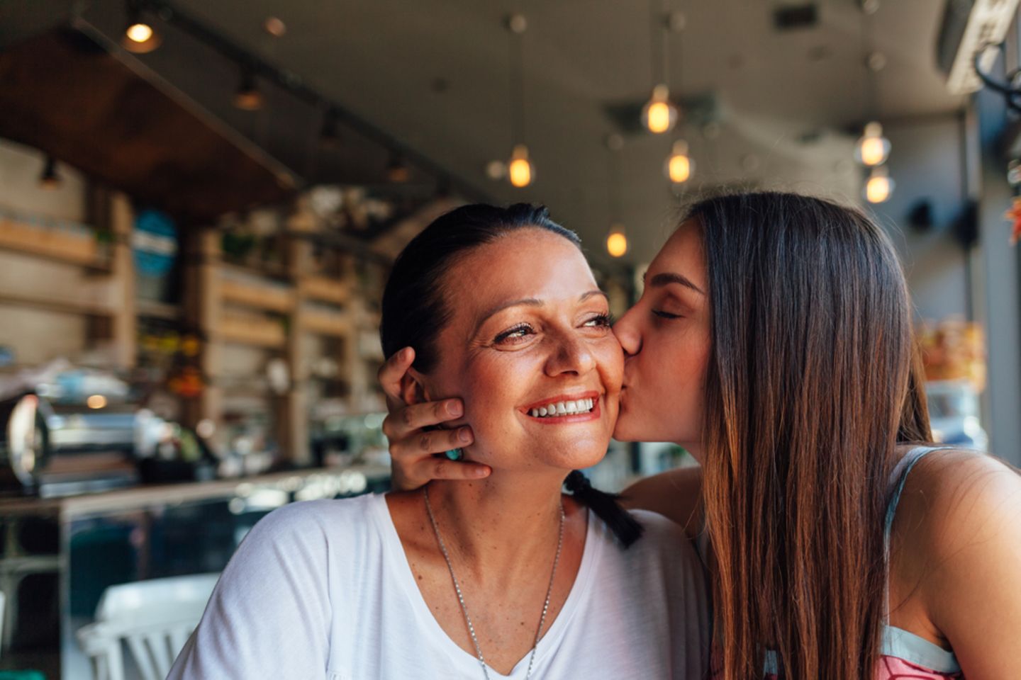 Mutter-Tochter-Tattoo: Tochter küsst ihre Mutter auf die Wange