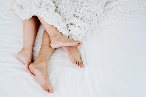 Phubbing: Ein Pärchen im Bett, man sieht nur die Füße