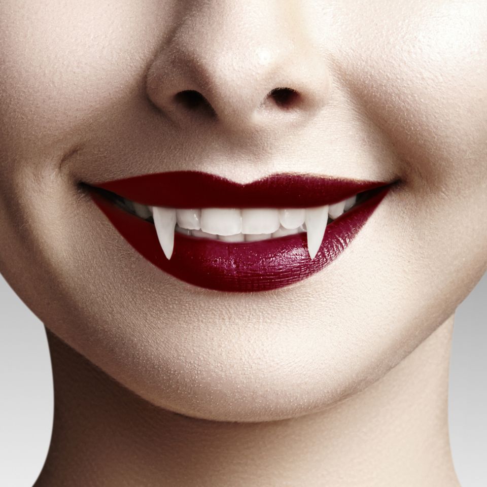 Vampir schminken: Frau mit roten Lippen und Vampir-Zähnen