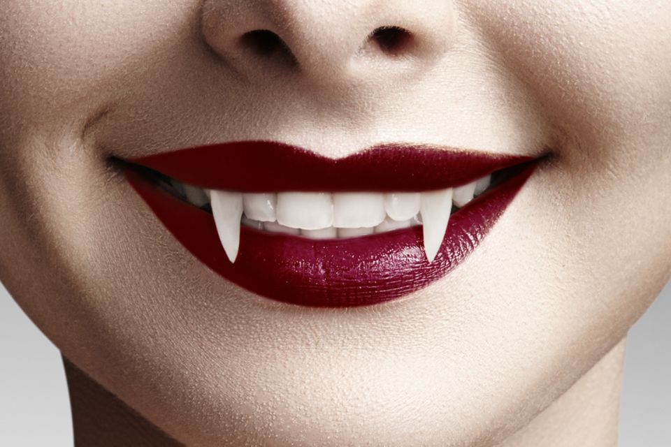 Vampir schminken: Frau mit roten Lippen und Vampir-Zähnen