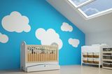 Wand streichen Ideen: Kinderbett vor blauer Wand mit aufgemalten Wolken