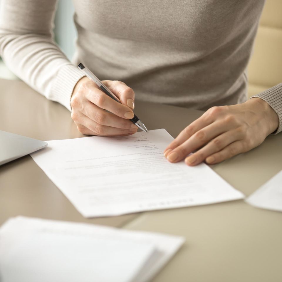 Unterschrift bei Online-Bewerbungen: Frau unterschreibt Dokument