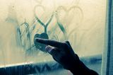 Liebeskummertipps der Redaktion: Eine Frau zeichnet Herzen an eine beschlagene Scheibe