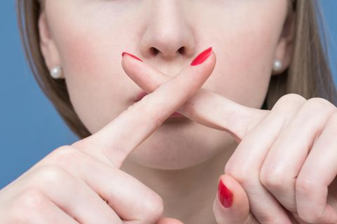 Lebenslügen: Eine Frau kreuzt die Finger vor ihrem Mund