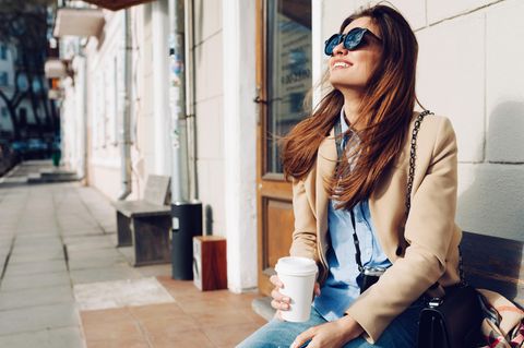 5-Minuten-Pause: Eine entspannte Frau mit Kaffee und Sonnenbrille