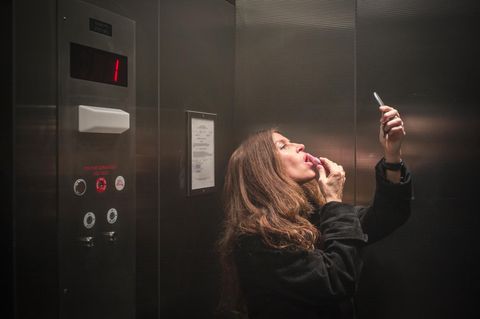 Partnersuche ab 50: Fast unmöglich?: Frau schminkt sich mit Handspiegel im Fahrstuhl