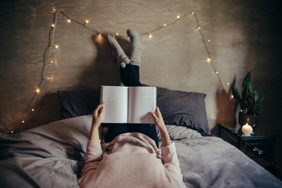 Gemütlichkeit: Frau liegt im Bett und liest
