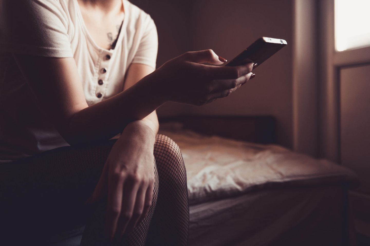 Fremdgehen: Frau sitzt im Dunklen vor ihrem Handy