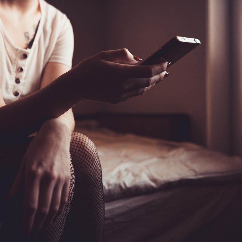 Fremdgehen: Frau sitzt im Dunklen vor ihrem Handy