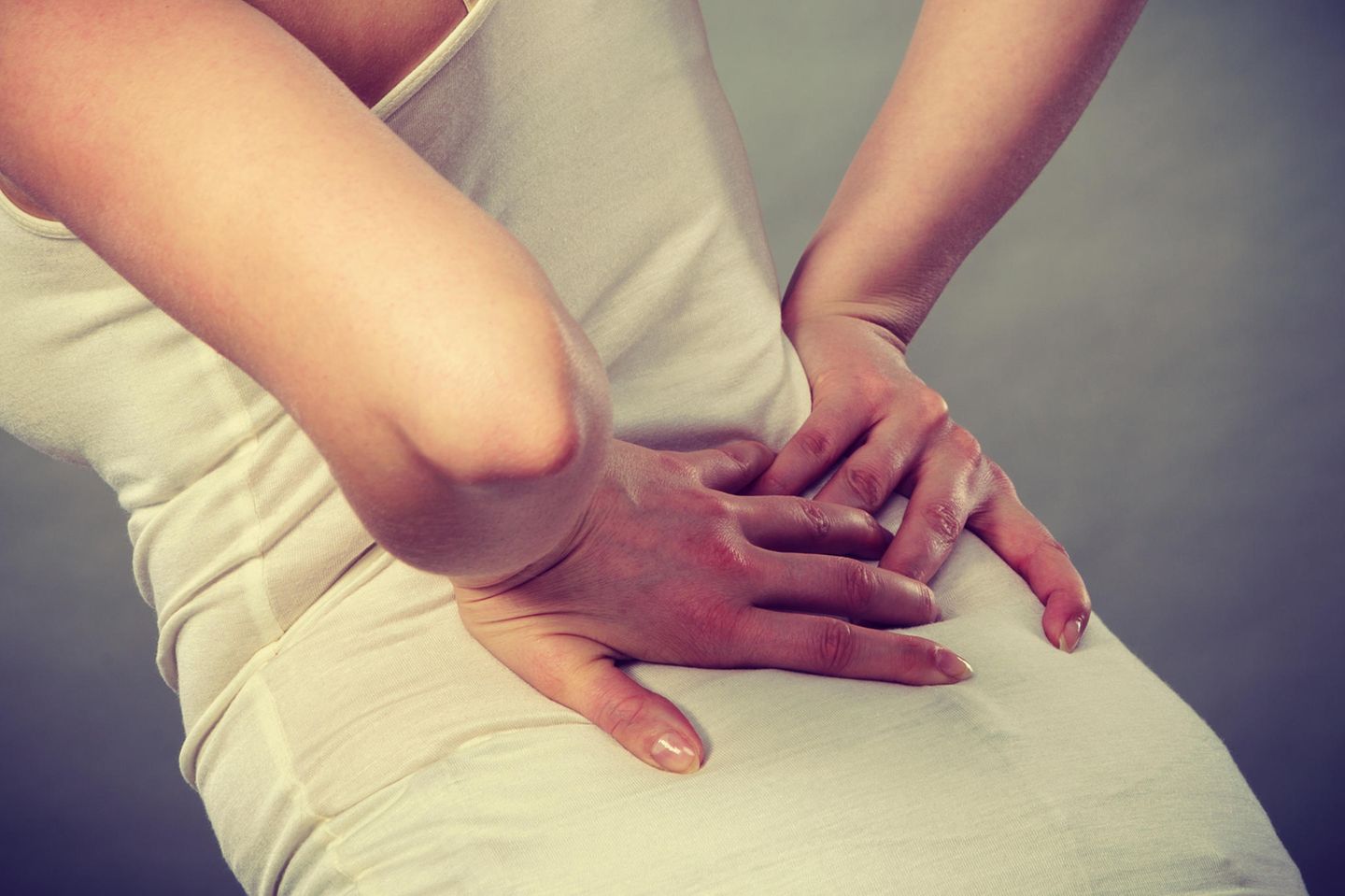Kreuzschmerzen: Frau hält sich den Rücken